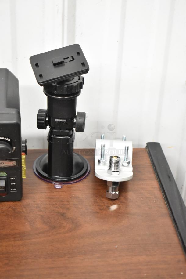 Uniden Pro505XL radio and mounting accessories on wooden surface. Black radio, black mount, white bracket with screws.