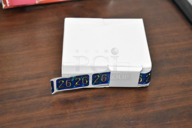 White box with holographic "26" stickers partially visible, on a wooden surface.
