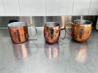 Assorted copper Moscow Mule mugs by Commercial Barware, featuring hammered copper and stainless steel, with visible branding.