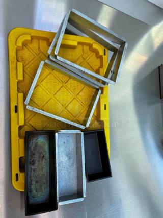 Assorted commercial baking pans and cake frames in stainless steel and aluminum, in remarkable condition, on a yellow tray.