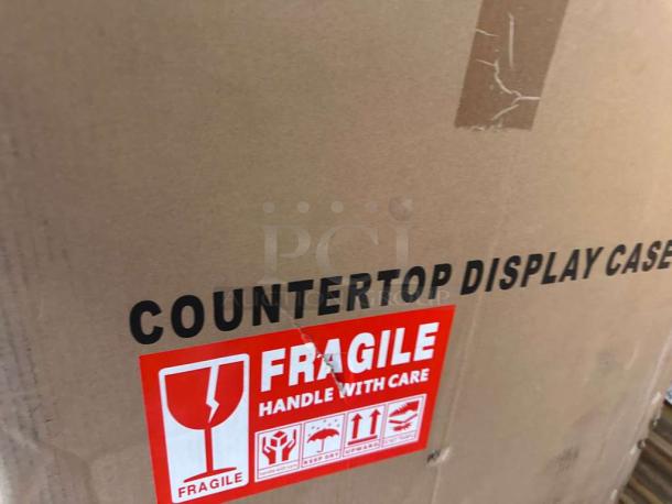 Sealed box of KoolMore DC-3CB Countertop Bakery Display Case, brand new condition, with "Fragile" and handling labels.