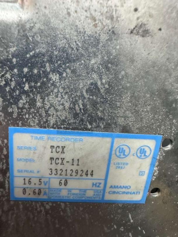 Amano TCX-11 time recorder clock label showing model, serial number 332129244, voltage 16.5V, UL listed.
