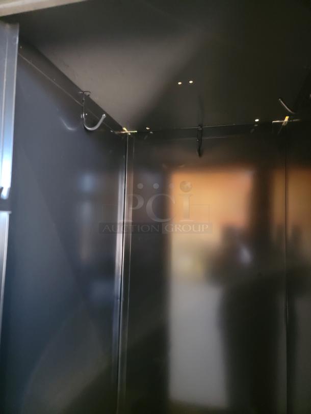 Interior of Tennsco black steel locker, featuring built-in hooks for hanging. Durable construction suitable for commercial use.