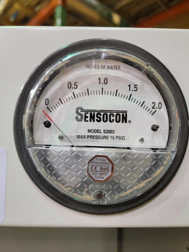 "Close-up of Sensocon Model S2002 pressure gauge, showing measurements in inches of water. Max pressure is 15 PSIG."