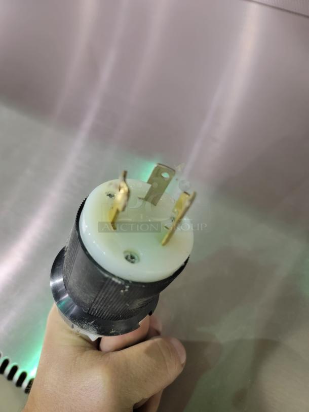 Hand holding a power plug for The Baker Company EdgeGard HF SG6252 clean bench, showing plug details.