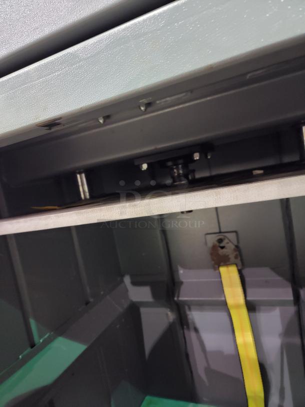 FOX Compactors 2430 industrial waste compactor interior view, showcasing steel frame and specialized bin with yellow strap.