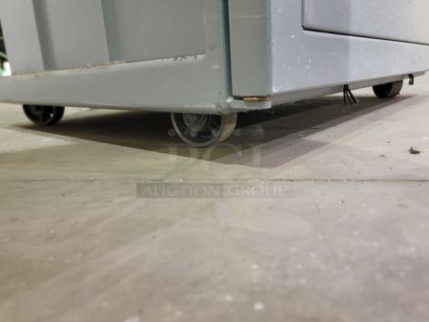 Close-up of the Fox Compactors 2430 waste compactor bin on casters, showing durable steel construction and mobility feature.