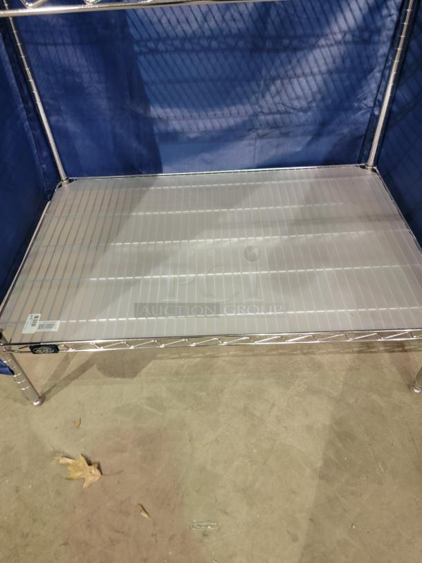 Nexel wire shelving unit with chrome frame and blue nylon enclosure; includes four tiers and bottom translucent liner.