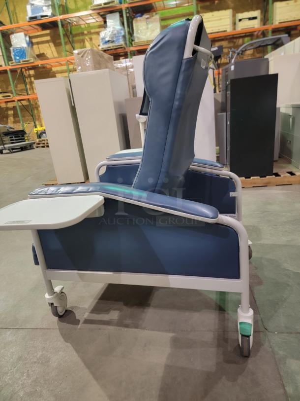 Winco Model 654 recliner with blue vinyl upholstery, dual side trays, heavy-duty casters, and a push bar.