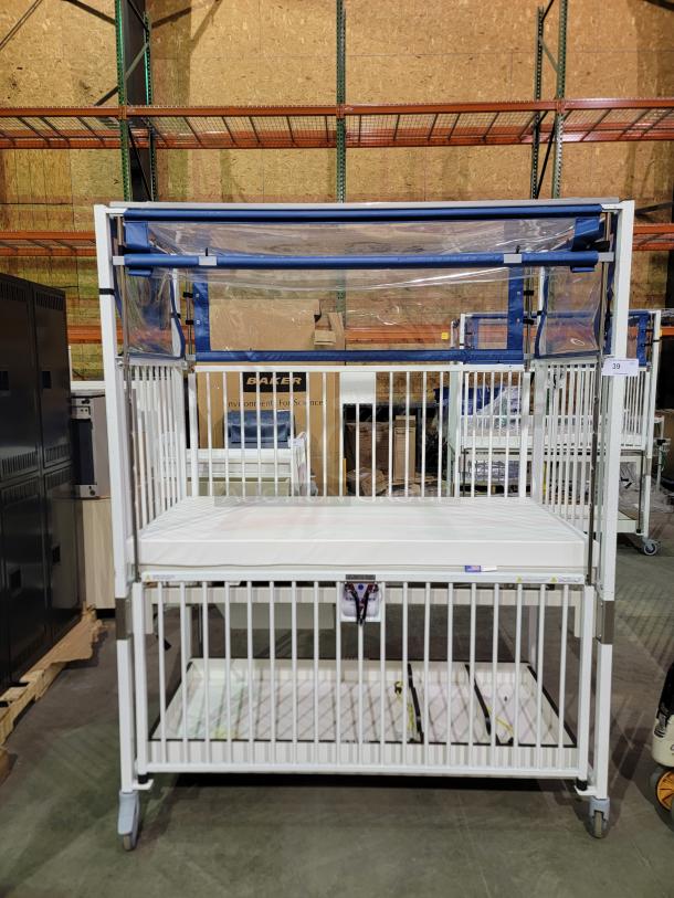Novum E1982CGT pediatric crib with manual crank, safety side-gate, swivel casters, and storage tray, in excellent condition.
