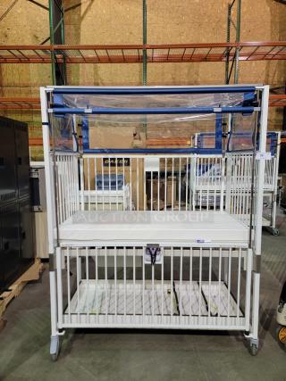 Novum E1982CGT pediatric crib with manual crank, safety side-gate, swivel casters, and storage tray, in excellent condition.