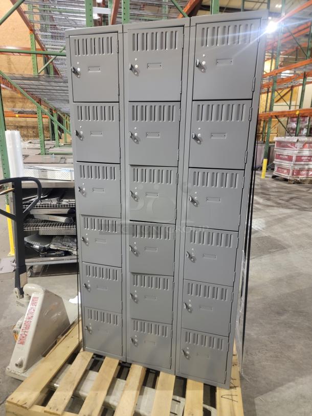 Lot of 3 Penco 6-tier box lockers on pallet. Gray steel with ventilation, recessed handles, and label holders. 54 compartments total.