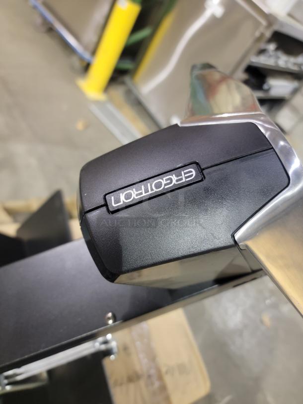 Ergotron WorkFit-S label on a workstation mount, detail view, showcasing the brand logo on a sleek black and silver finish.