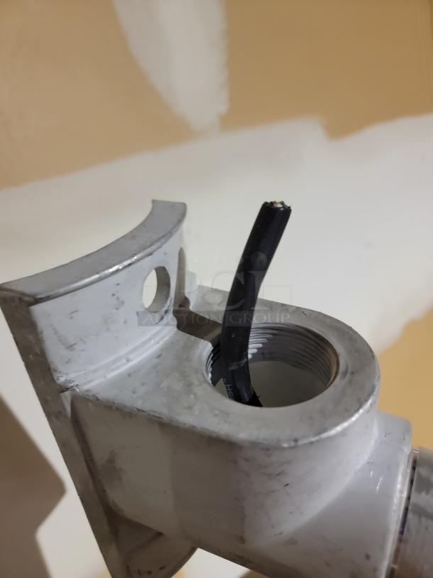 Close-up of a metal housing for Campbell pedestrian crossing signal, showing an open conduit with black multi-strand wiring.