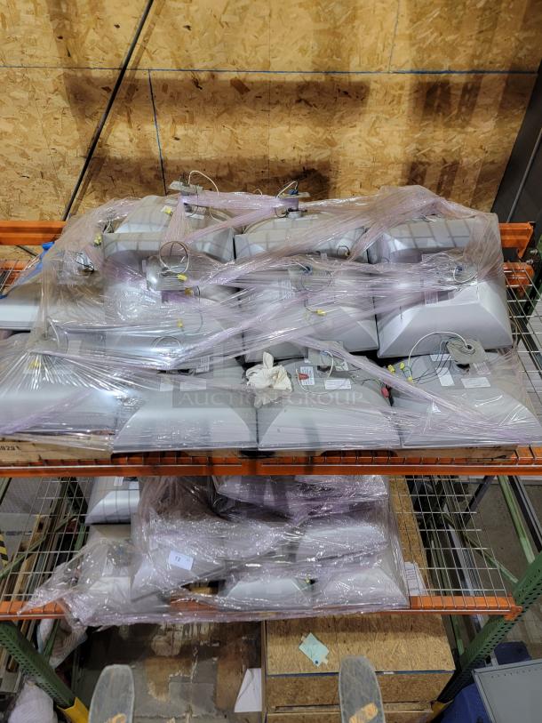 Two pallets of LSI Industries Crossover XPGP LED canopy lights, wrapped in plastic, stacked in a warehouse.