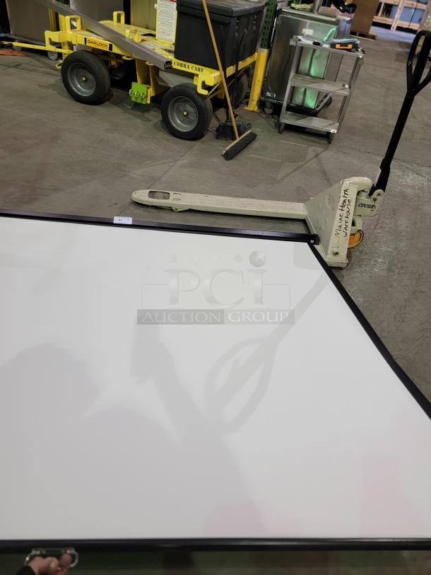 Quartet 7' projection screen with matte white surface, black metal housing, and pull-down mechanism. Includes mounting hardware.