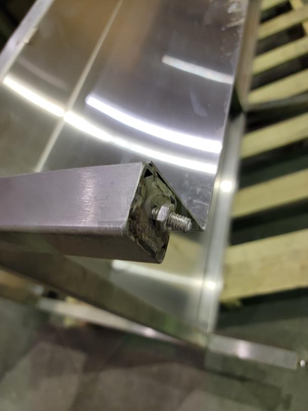 Close-up of heavy-duty stainless steel prep table with 24-inch sink, showing reinforced corner and sturdy construction detail.