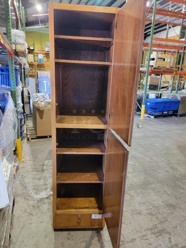 Solid wood storage cabinet with a honey-oak finish, featuring two doors, adjustable shelves, and a bottom drawer. Mid-century style.
