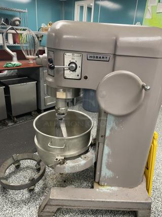 Hobart H-600 commercial mixer with stainless steel bowl, dough hook, and wire whip on steel rolling base. Good condition.