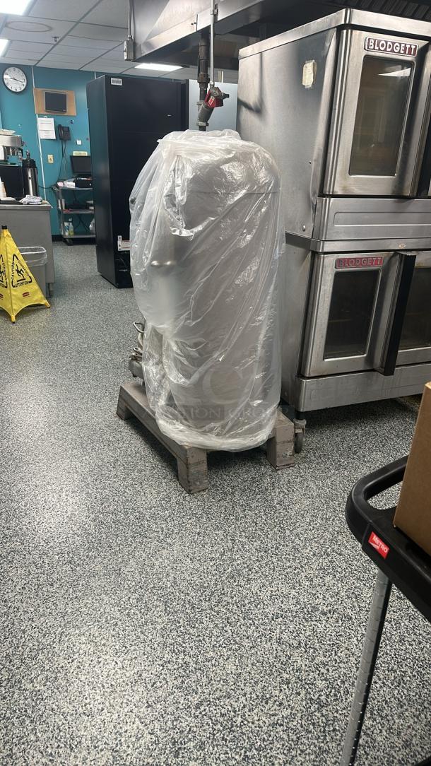 Hobart H-600 commercial mixer covered with plastic on a rolling base, includes stainless steel bowl, dough hook, wire whip.