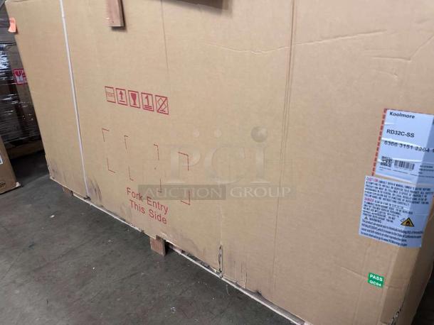 New KoolMore RD32C-SS refrigerated display case in packaging, ready for commercial use. Tags indicate model and handling instructions.