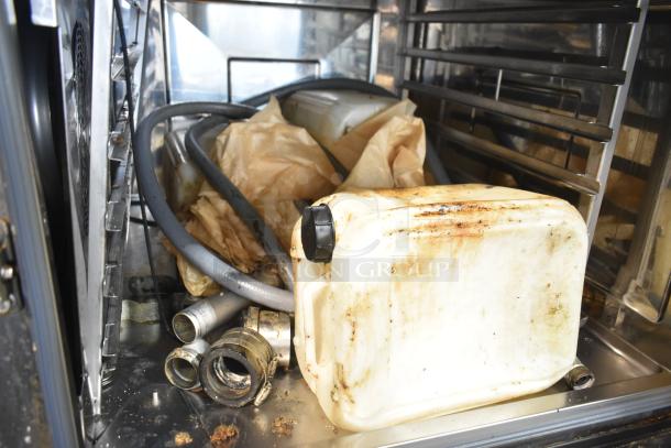 Interior of a 2021 Rational iCombi Pro convection oven showing hoses, a stained container, and metal fittings.