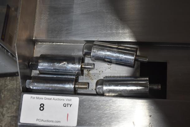 Five metal cylinder components with threaded ends on a metal surface. Label reads PCI Auctions, QTY 8.