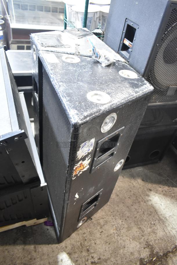 Two large black speakers with visible wear, featuring side handles and sticker labels. Ideal for sound events.