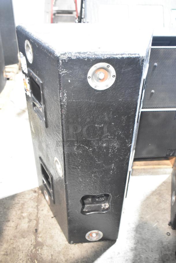 Two black rectangular speakers with visible wear, featuring metal corner reinforcements and recessed handles.