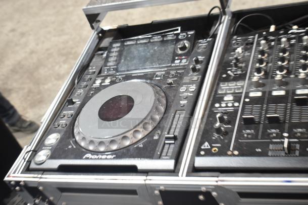 Pioneer DJ station with CDJ-2000 and DJM-900 Nexus in road case, showing control knobs and digital display.