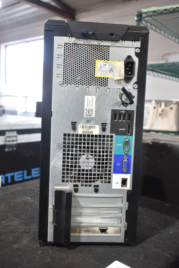 Rear view of a Dell computer tower featuring various ports including USB, eSATA, VGA, and Ethernet. Visible product label and power supply input.