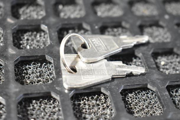 Two metallic keys on a keyring, placed on a textured black surface, each marked "H983".