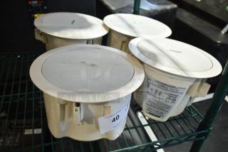 4 Bose FreeSpace DS 16F Loudspeakers, white, used, visible labels with specifications, shown on a metal shelf.