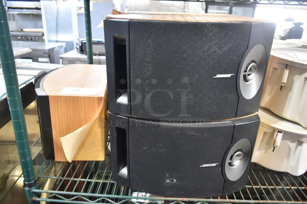 Five speakers including Bose 201 V, in used condition. Black and wood finish, visible wear. Ideal for audio enthusiasts.