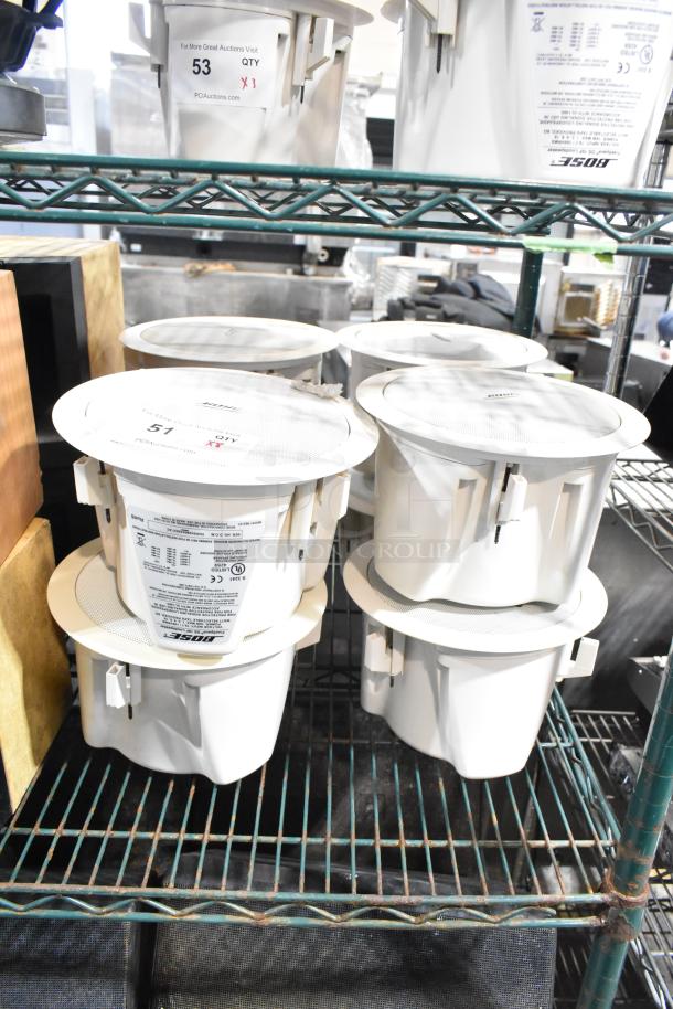 Four Bose FreeSpace DS 16F loudspeakers, white, on a shelf. Model labels visible, appear new. Bid includes all four units.