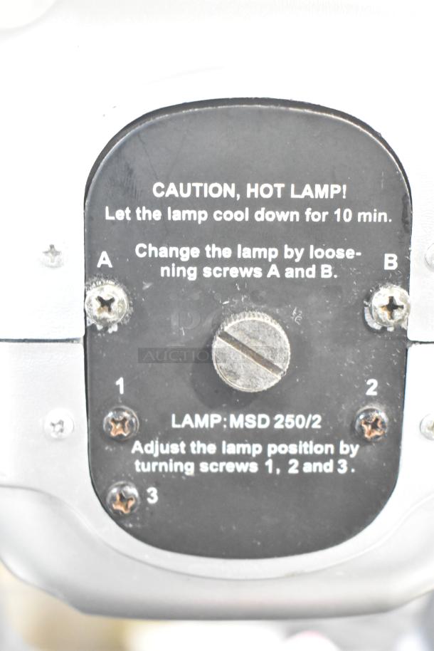 Close-up of American DJ Accu Spot 250 II light housing with caution label and screw adjustment instructions visible.