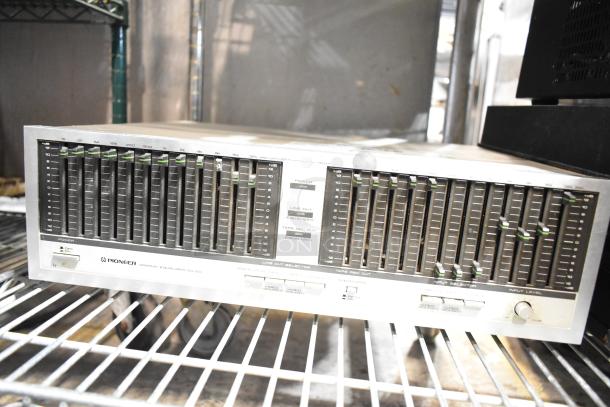 Pioneer SG-60 graphic equalizer on metal shelving, featuring multiple frequency sliders and input/output selectors.