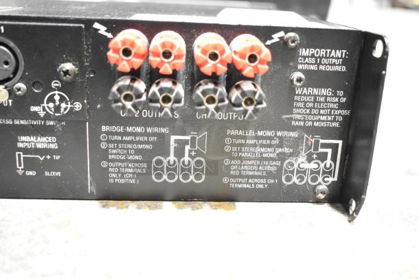 Rear panel of Crown Macro Tech amplifier showing wiring instructions and output terminals. Visible wear on the surface.