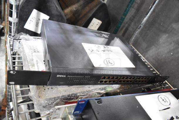 Dell PowerConnect 2024 switch on shelf with visible ports, alongside wrapped items with auction labels.