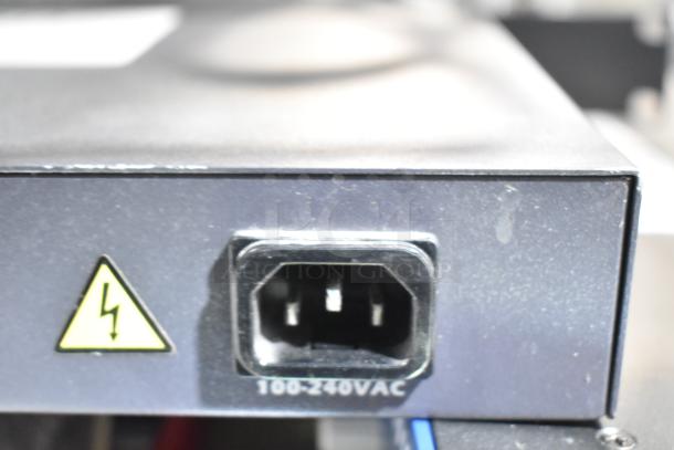 Electrical plug on the back of a device, marked with a 100-240VAC rating and a caution symbol, likely from one of the auction items.