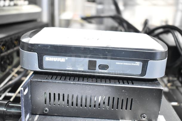 Shure PG4 Internal Antenna Diversity audio receiver with visible controls and markings, stacked on equipment. Signs of use.