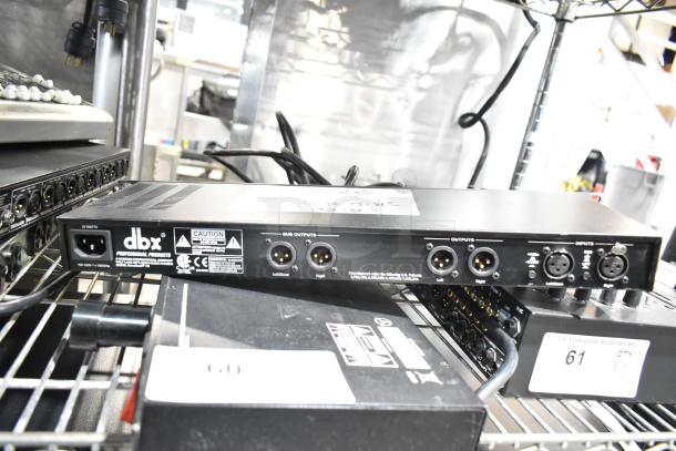 Three audio devices, including Shure PG4, DBX DriveRack PX, Samson PowerBrite Pro15, shown on metal shelves. Visible labels and connectors emphasize functionality.