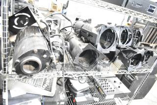 9 GoboSource ES-B10E stage lights on metal shelving, showing robust construction. Ideal for stage setups.