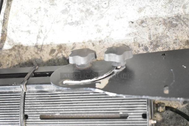 Close-up of GoboSource ES-B10E stage light hardware. Two adjustment knobs on a metal bracket, moderate wear visible.