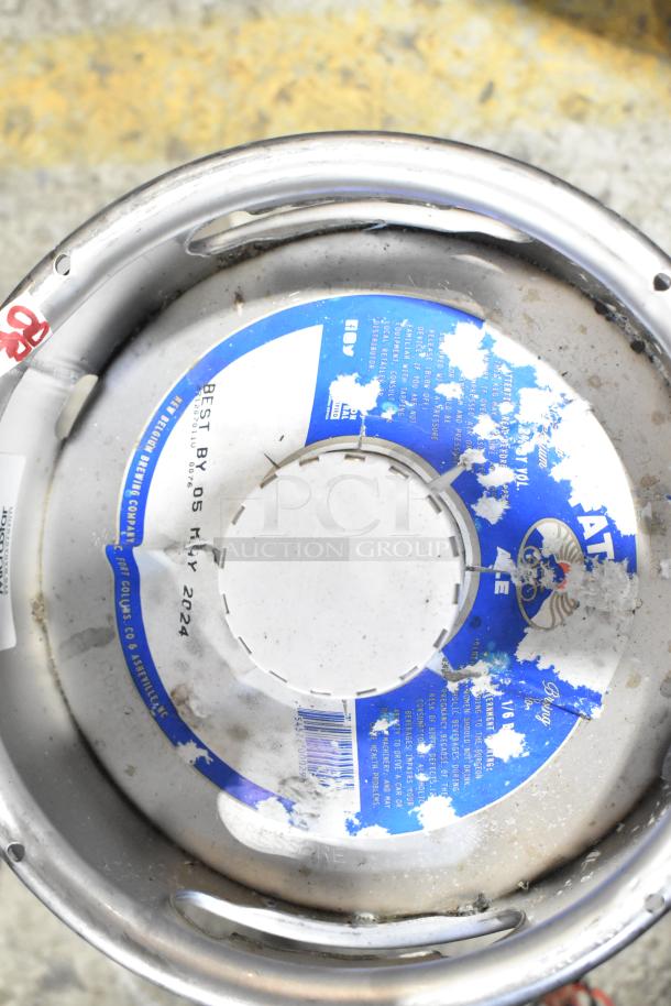 Two sixth barrel kegs with visible wear, featuring a blue label marked "Best By 05 May 2024," ready for auction.