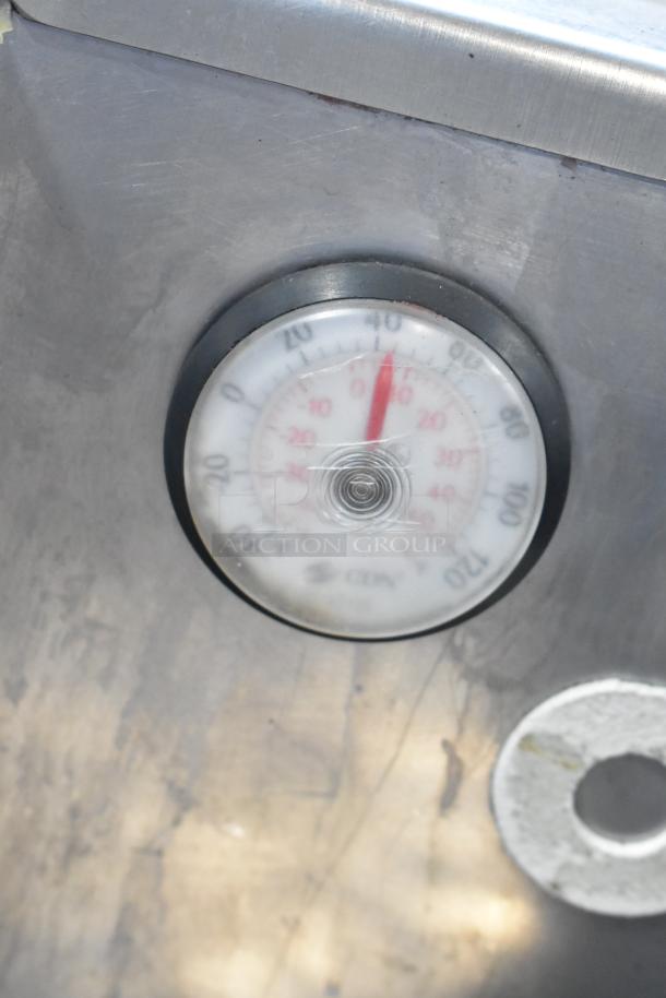 Thermometer dial on stainless steel pizza prep table, showing temperature in Celsius.