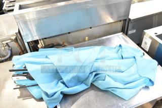 Two blue patio umbrellas folded, on metal surface. Includes visible tag marked "QTY 2." Appears in good condition.