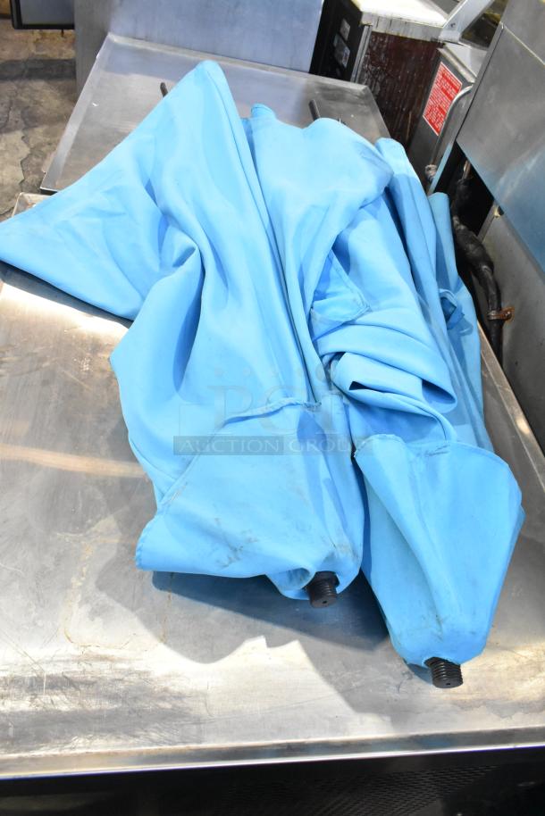 Two blue patio umbrellas, collapsed, slightly worn, with metal bases. Auction includes two umbrellas per bid.