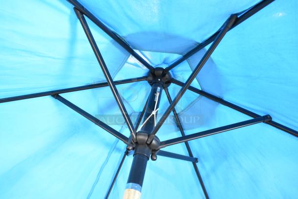 Blue patio umbrella with sturdy metal frame, viewed from underneath. Excellent condition, vibrant color, ideal for outdoor use.