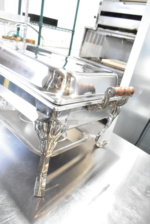 Brand new countertop chafer with elegant metal design, wooden handles, minor scratches and dents visible on stainless steel.